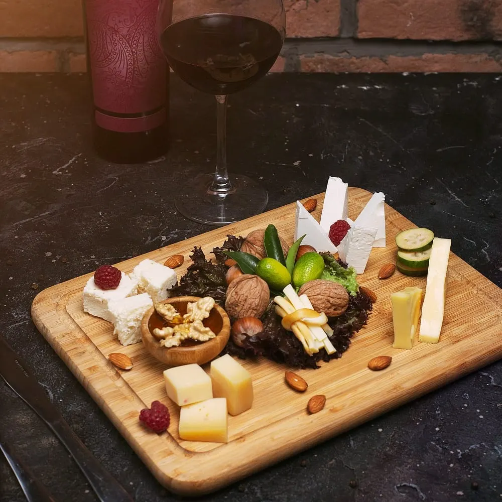 Planche apéritive de fromages, fruits secs et verre de vin rouge