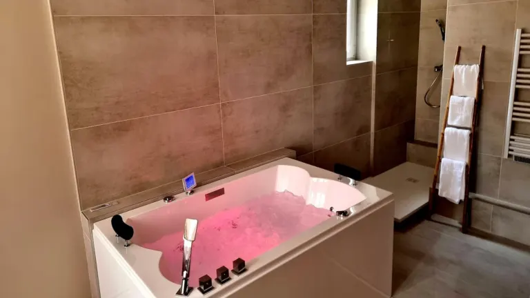 Baignoire balnéo duo éclairée en rose et porte-serviettes