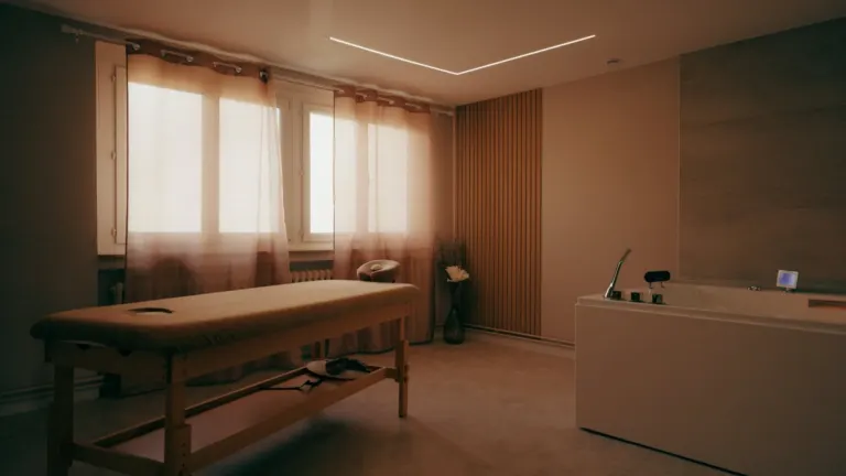 Espace bien-être : table de massage et baignoire balnéo face aux fenêtres