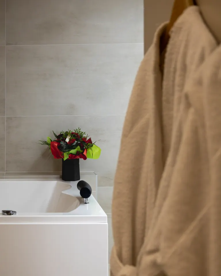 Peignoir suspendu près de la baignoire balnéo et bouquet de roses