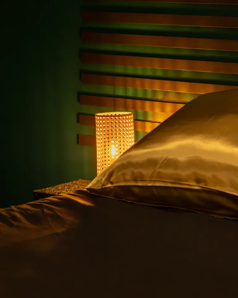 Oreiller en satin doré et lampe de chevet sur le lit de l'espace nuit