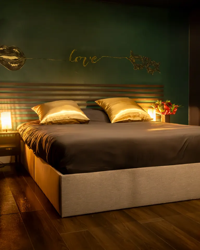 Lit king size aux coussins dorés sous l'inscription « love », Donjon des Sens
